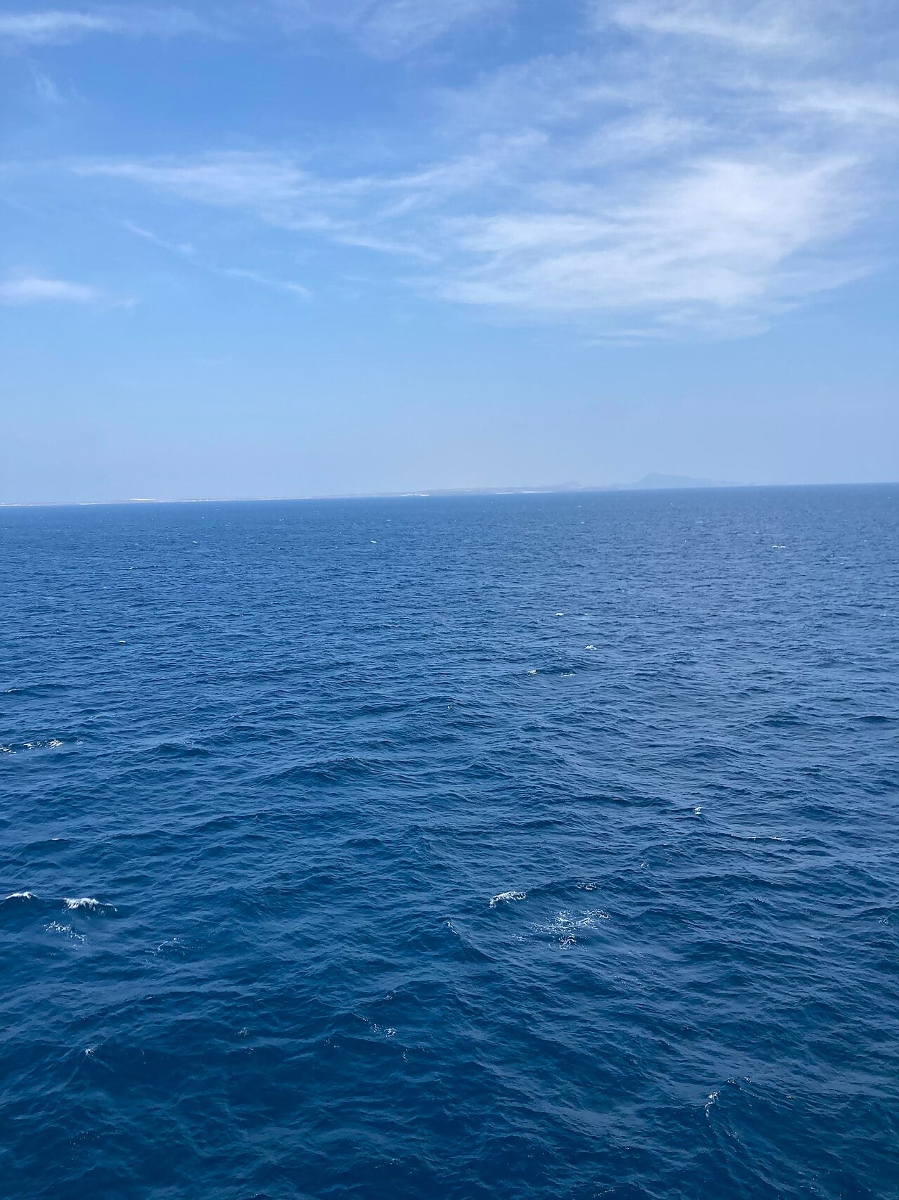 Open blue water under a pale sky with a faint coastline on the horizon