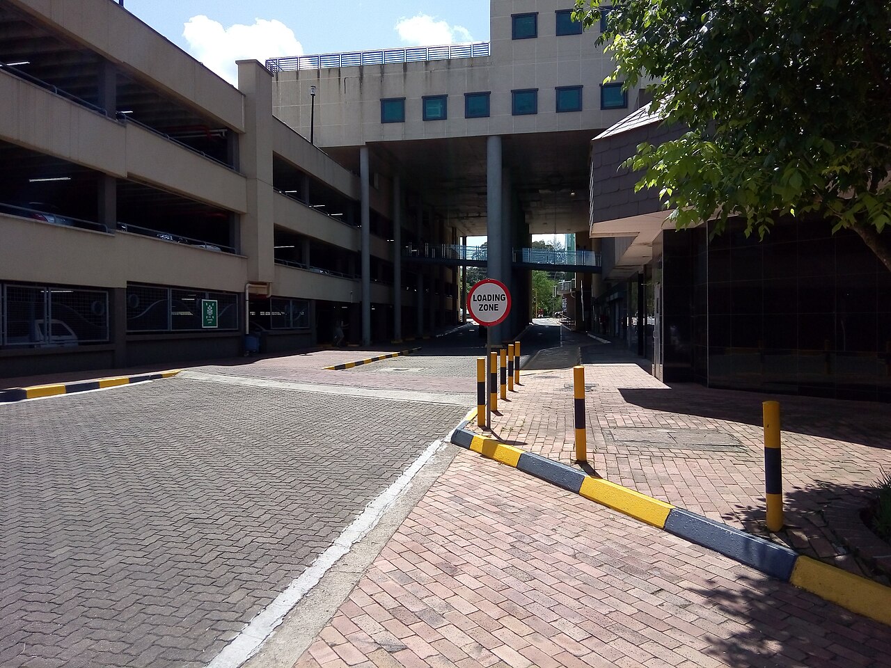 Swazi Plaza complex in Mbabane with a multi-storey car park, a raised walkway and a loading zone sign