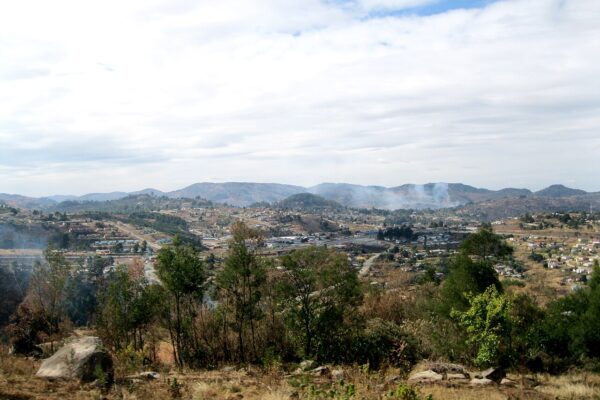 Houses and roads spread across green hills around Mbabane, the capital of Eswatini, under a cloudy sky