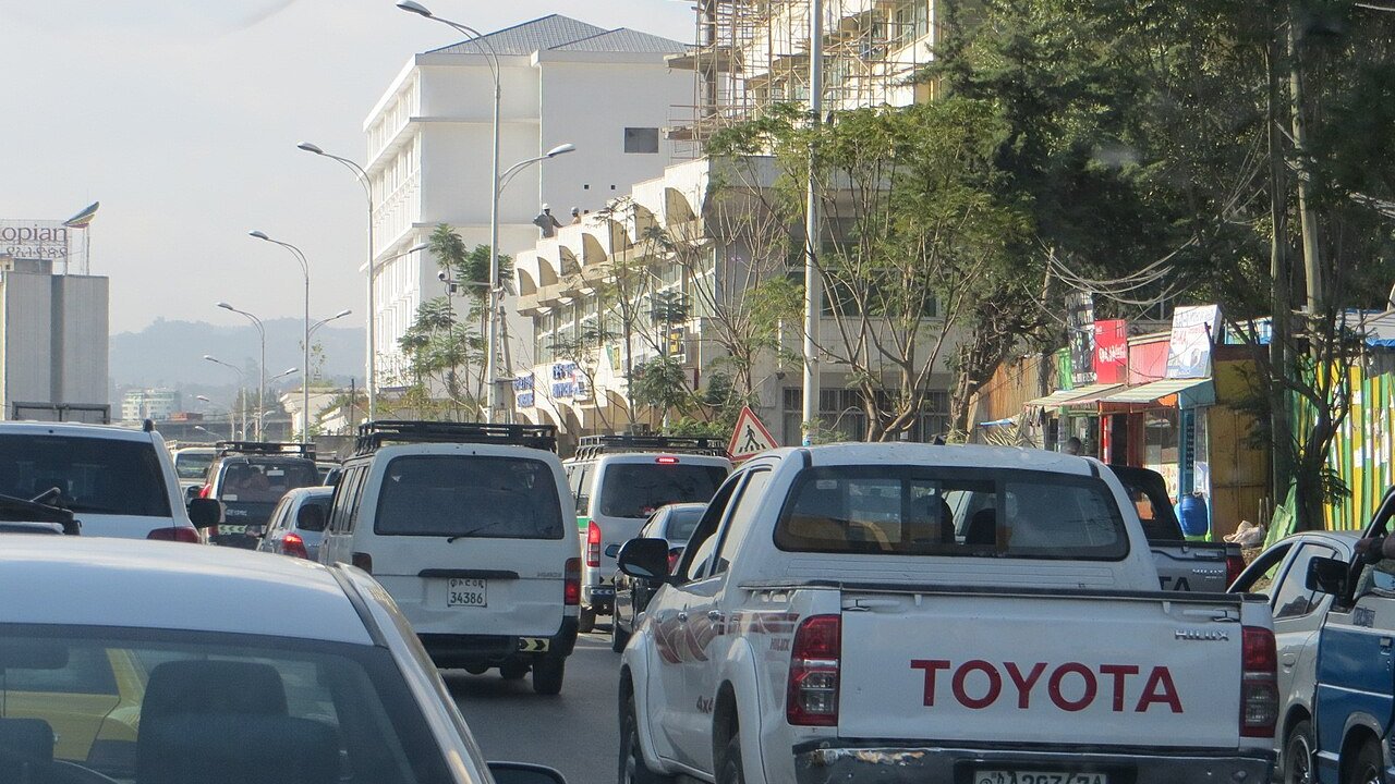 Heavy traffic of vans, pickup trucks and cars on a street in Addis Ababa, Ethiopia, with a scaffolded building behind