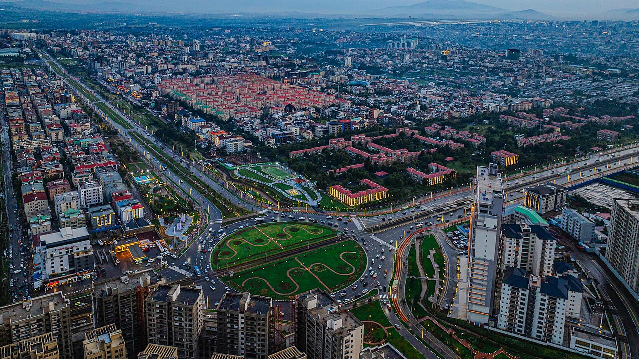 Aerial view of Addis Ababa at dusk with apartment blocks, a roundabout garden and lit avenues