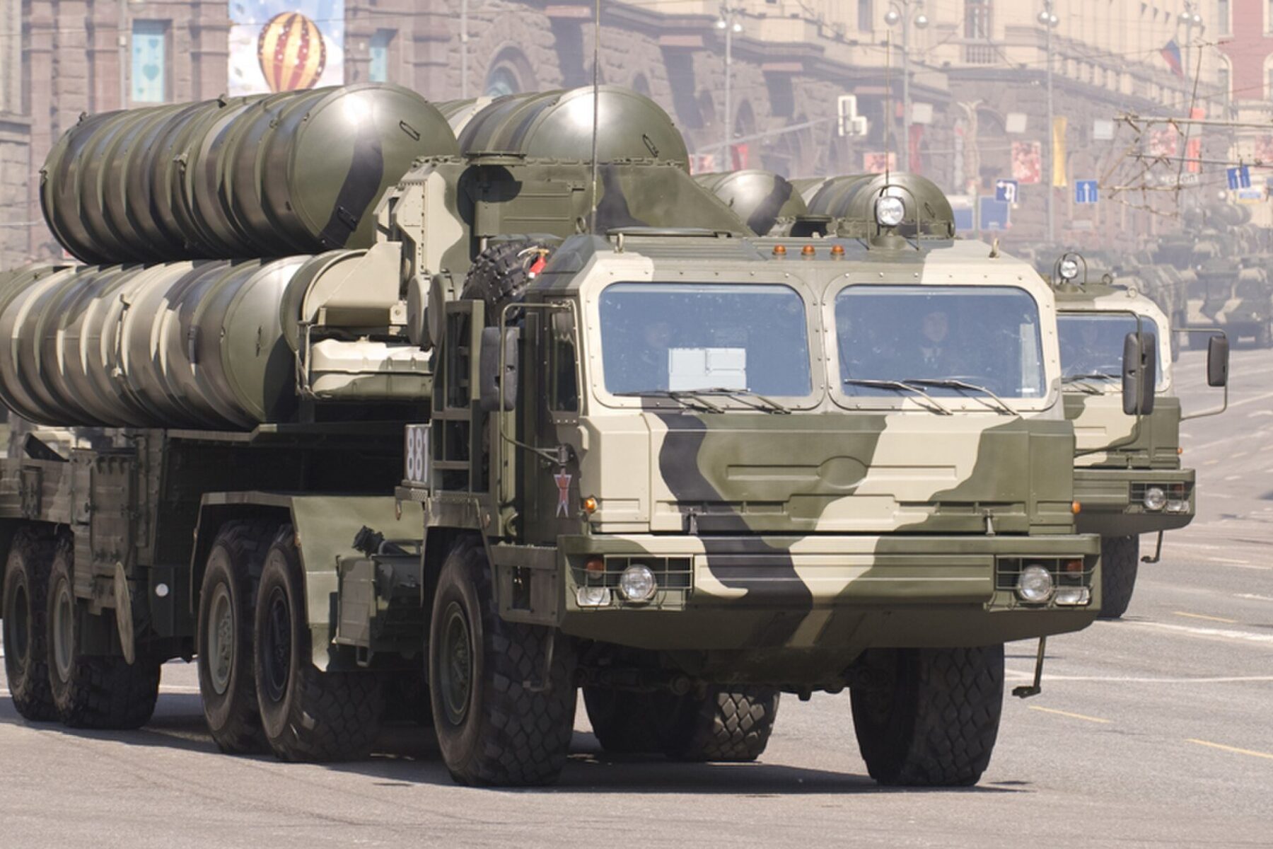 A camouflaged Russian S-400 air defence launcher truck with missile tubes raised drives down a city street during a parade