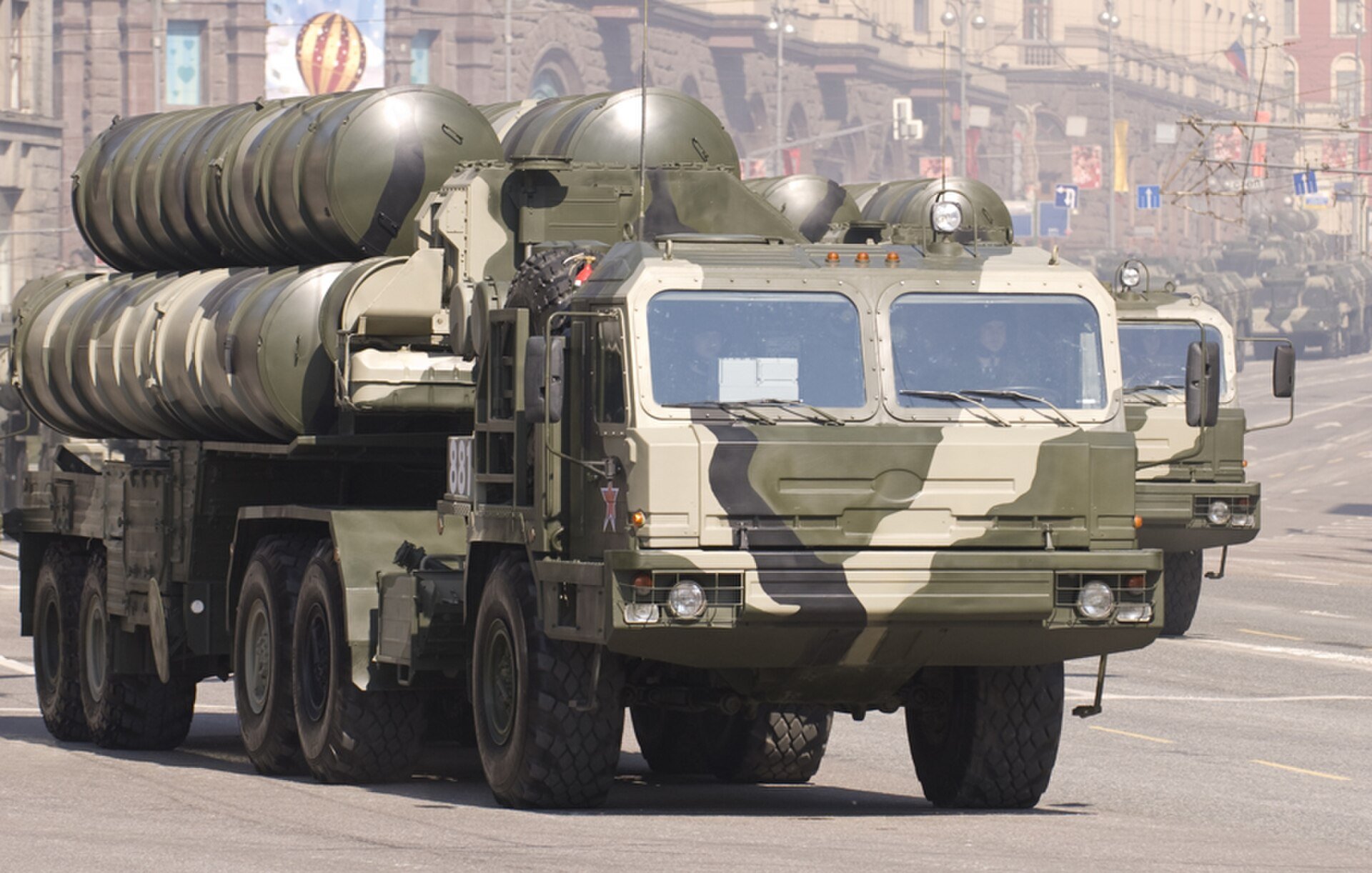 A camouflaged Russian S-400 air defence launcher truck with its missile tubes in travel position drives down a city street during a parade