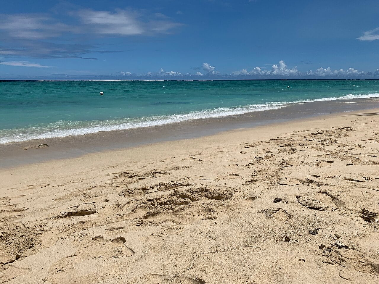 Turquoise lagoon and pale sand on the public beach at Flic-en-Flac, on the west coast of Mauritius.