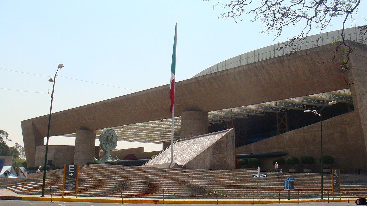 Front of the Auditorio Nacional in Mexico City, a concrete concert hall with a Mexican flag and wide steps.