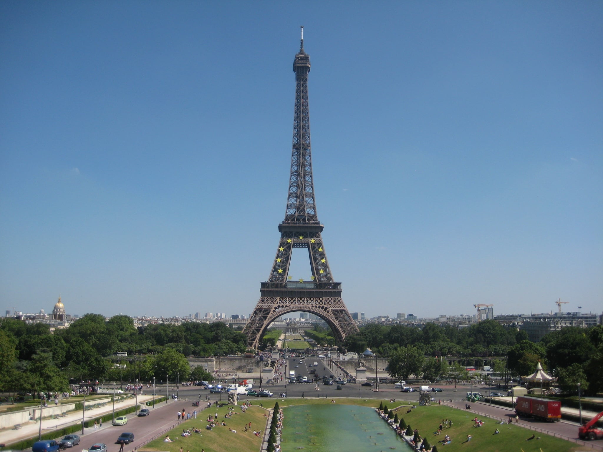 The Eiffel Tower under a clear blue sky, seen from the Trocadéro gardens with fountains and lawns in the foreground