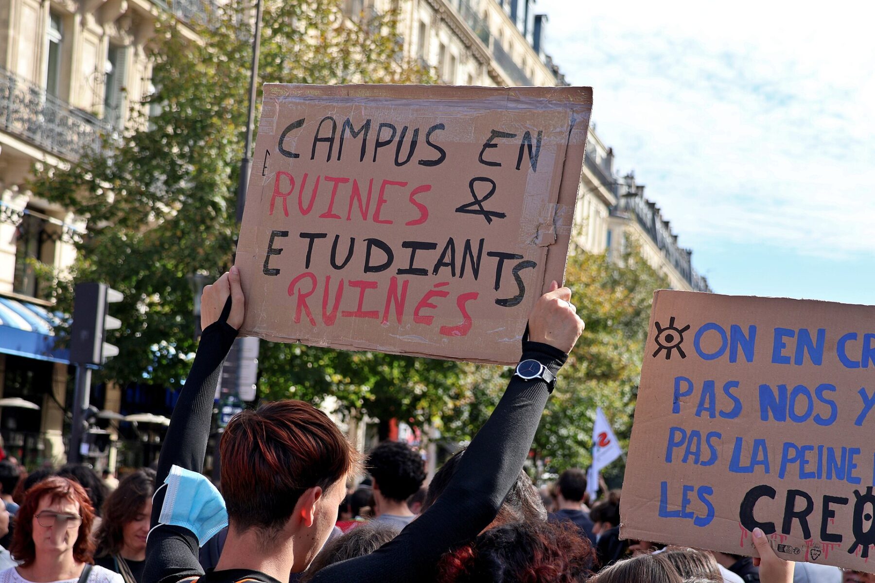 Students hold cardboard signs in a crowd during a march in Paris