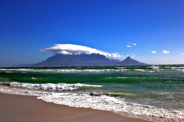 Table Mountain under a cap of cloud, seen across Table Bay from a beach north of Cape Town