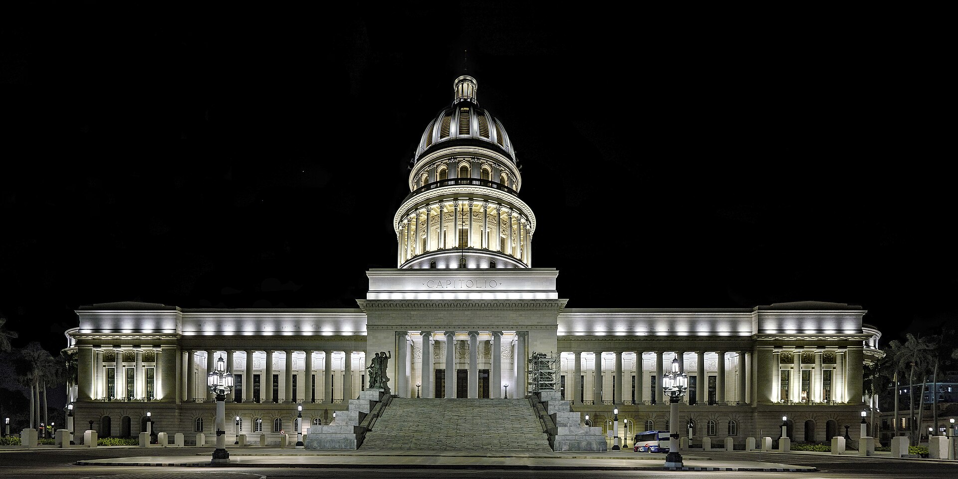 The domed Capitolio building in Havana lit up at night with its wide stone steps in front
