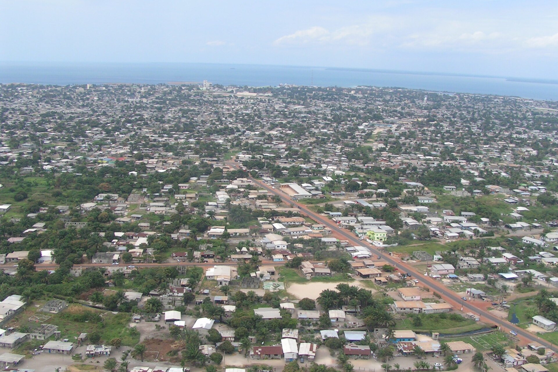 Aerial view of Port-Gentil, Gabon, with low-rise neighbourhoods, a main road and the Atlantic Ocean on the horizon.