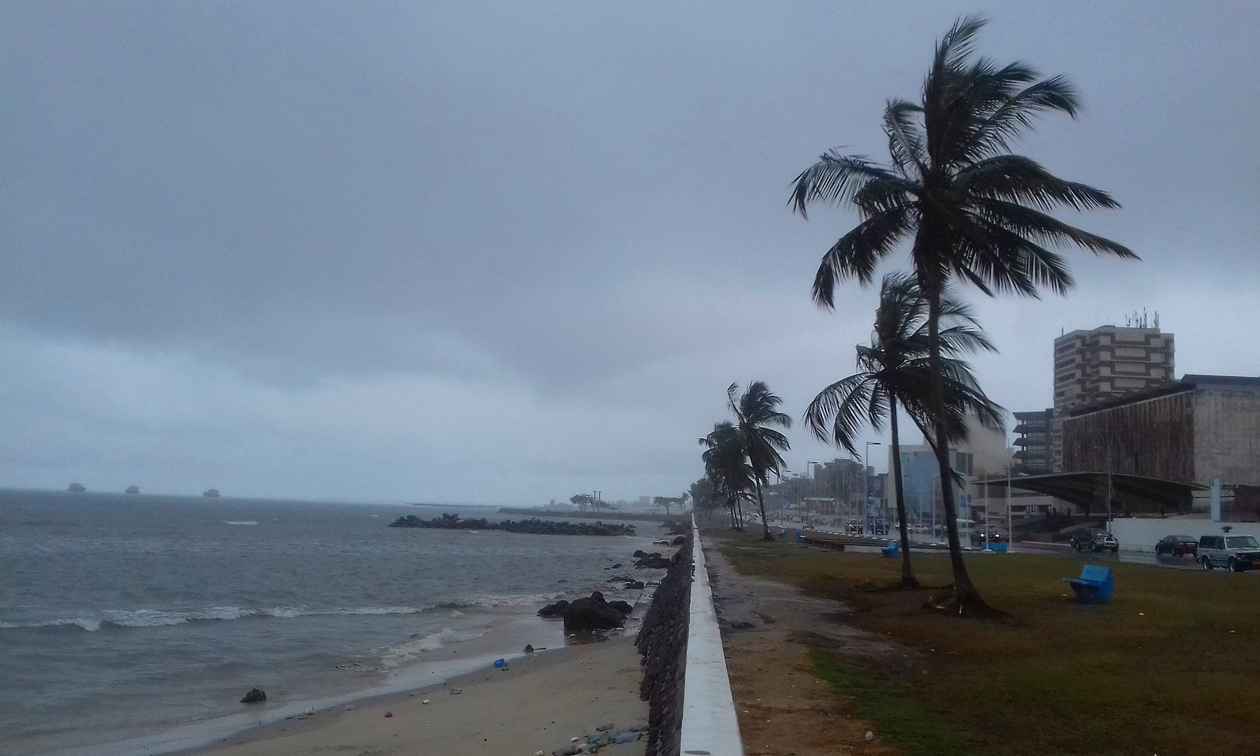 Libreville seafront in Gabon under grey skies, with palm trees, the coastal road and office buildings