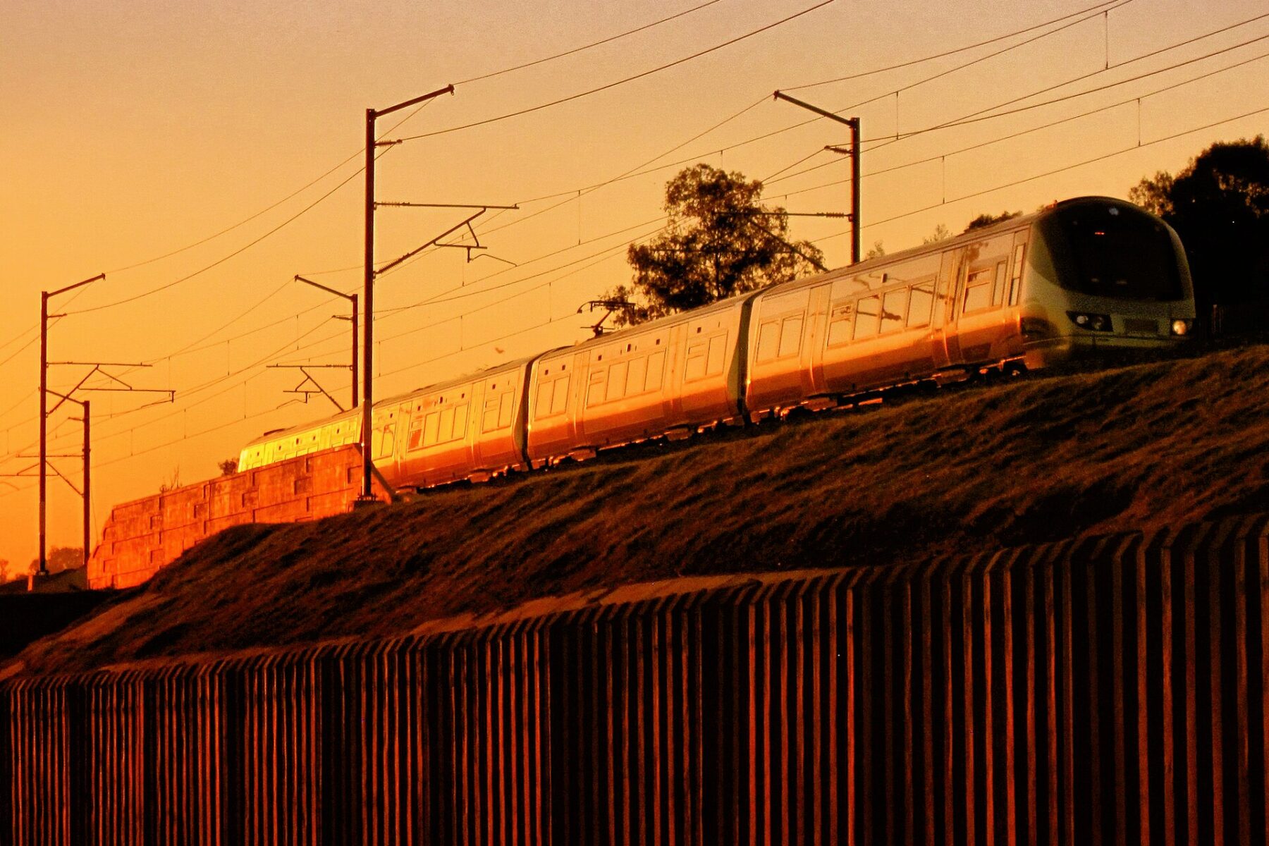 A Gautrain electric train on an embankment at Modderfontein in Gauteng, South Africa, lit by the evening sun