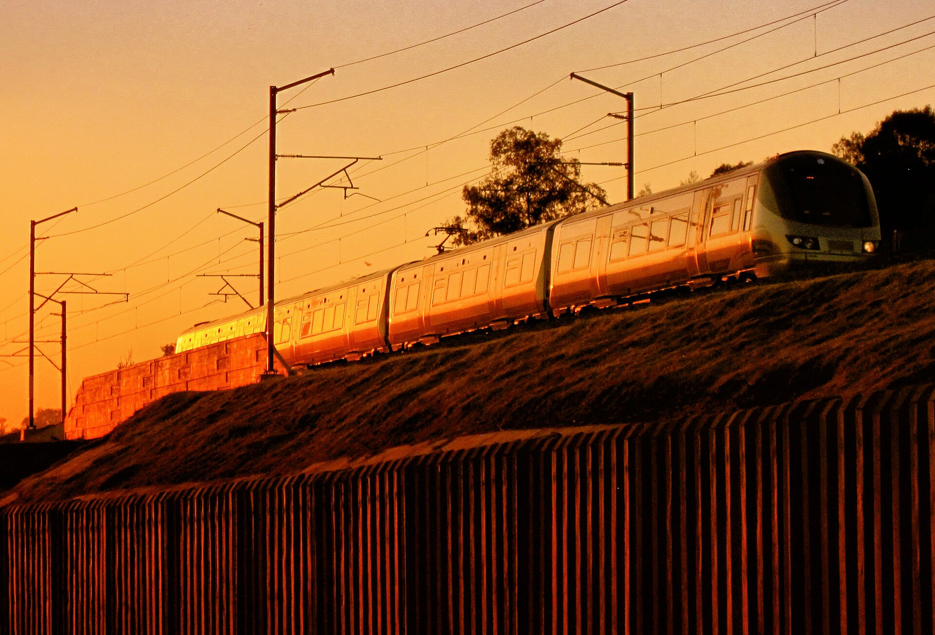 A Gautrain electric train on an embankment at Modderfontein in Gauteng, South Africa, lit by the evening sun