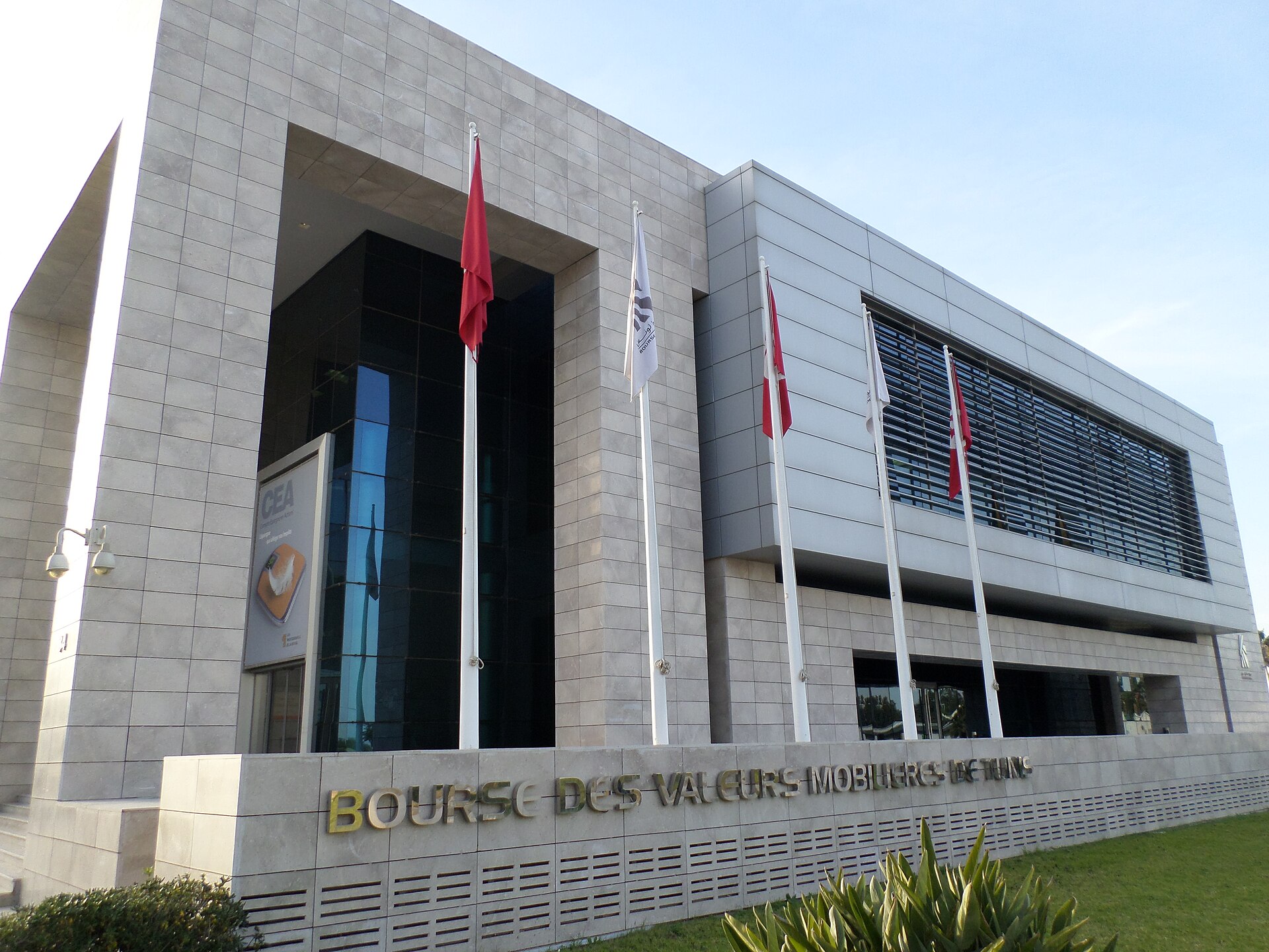 The stone-clad headquarters of the Tunis Stock Exchange with flagpoles and the words Bourse des Valeurs Mobilieres de Tunis on the wall