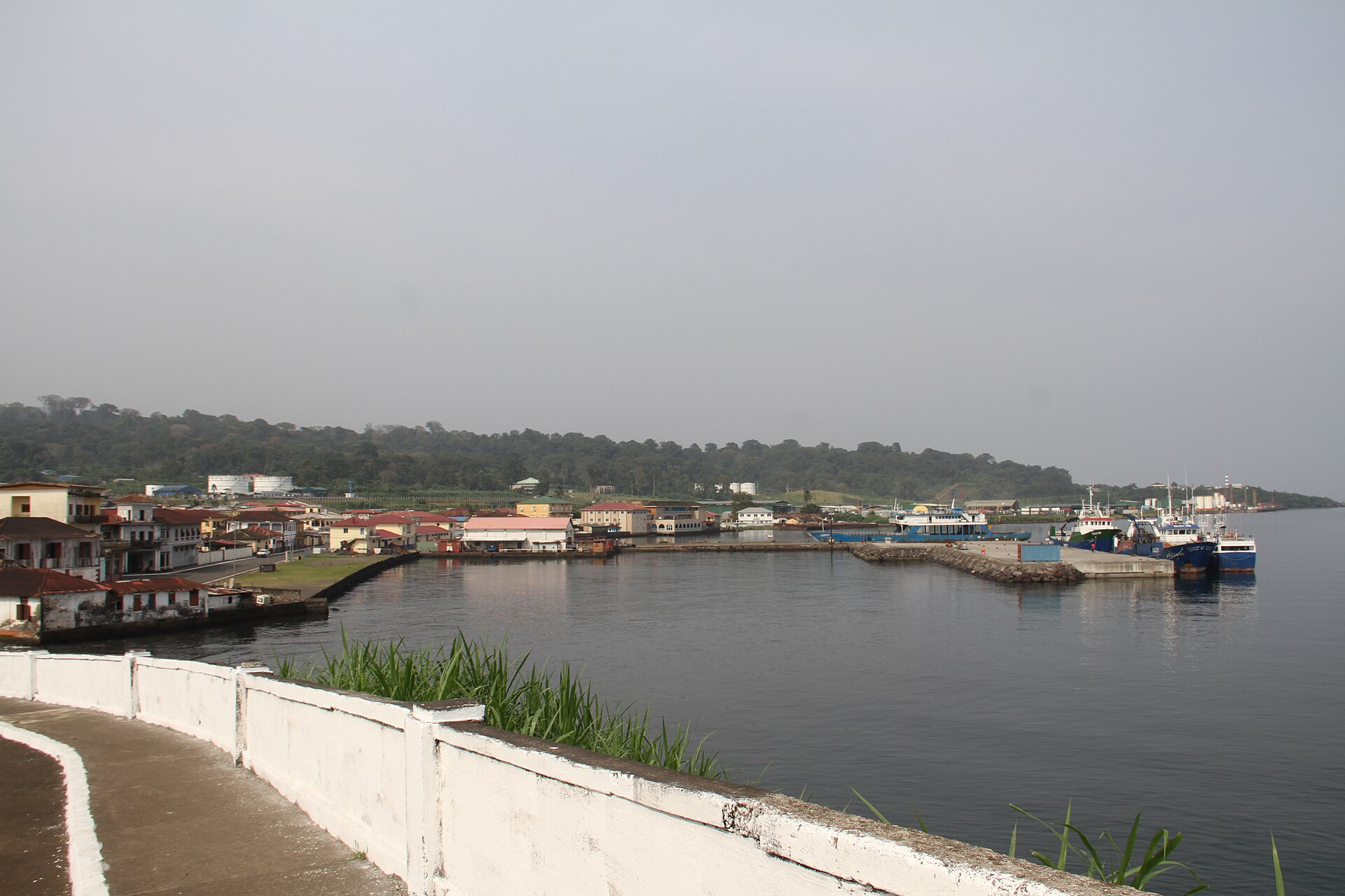 The small harbour of Luba on Bioko island, Equatorial Guinea, with houses on the shore, moored boats and a hazy sky