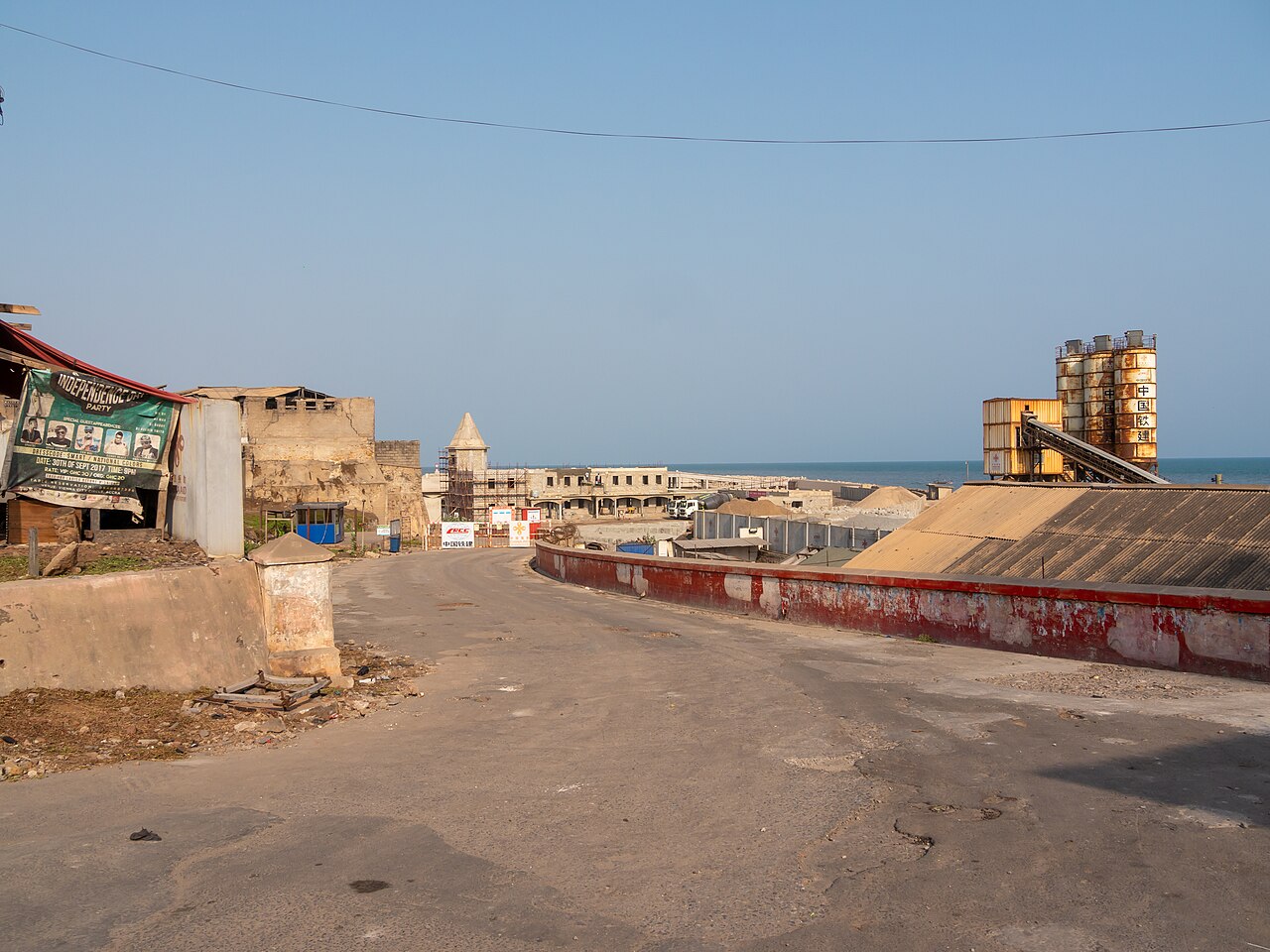 Seaside construction site in Jamestown, Accra, with cement silos marked in Chinese characters and a CRCC sign at the gate