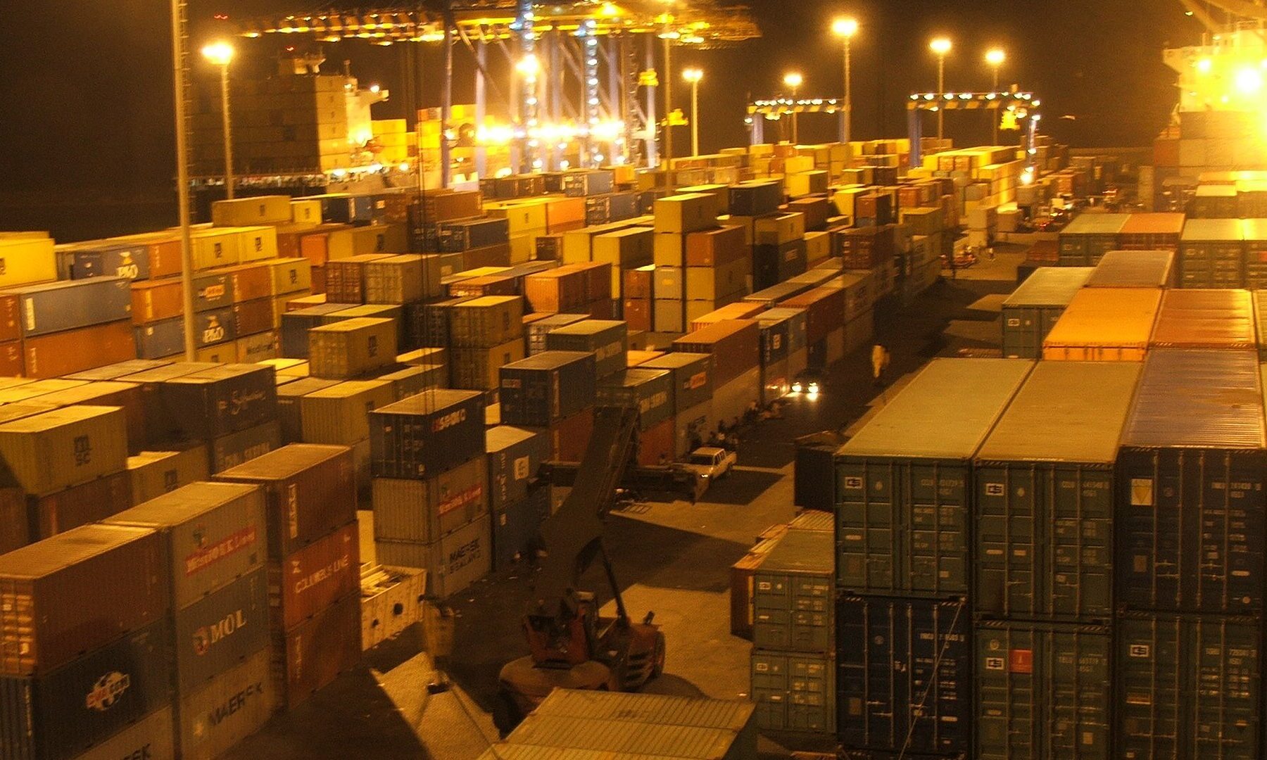 Stacked shipping containers under floodlights at night at the container terminal in Tema, Ghana