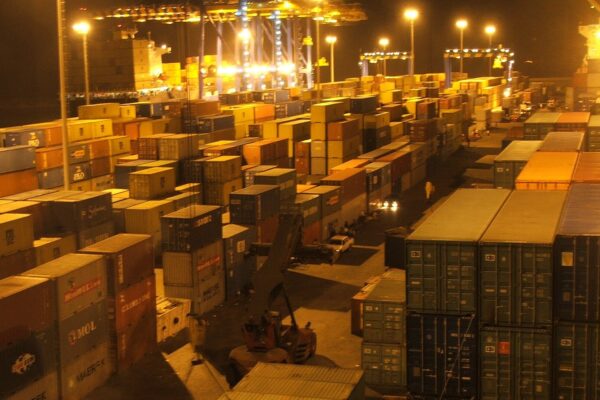 Stacked shipping containers under floodlights at night at the container terminal in Tema, Ghana