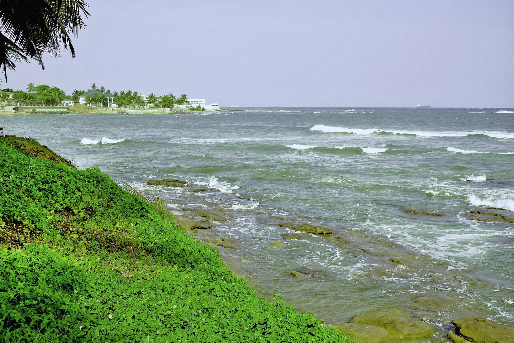 Waves on the rocky shore at Sekondi-Takoradi in Ghana, with ships on the horizon