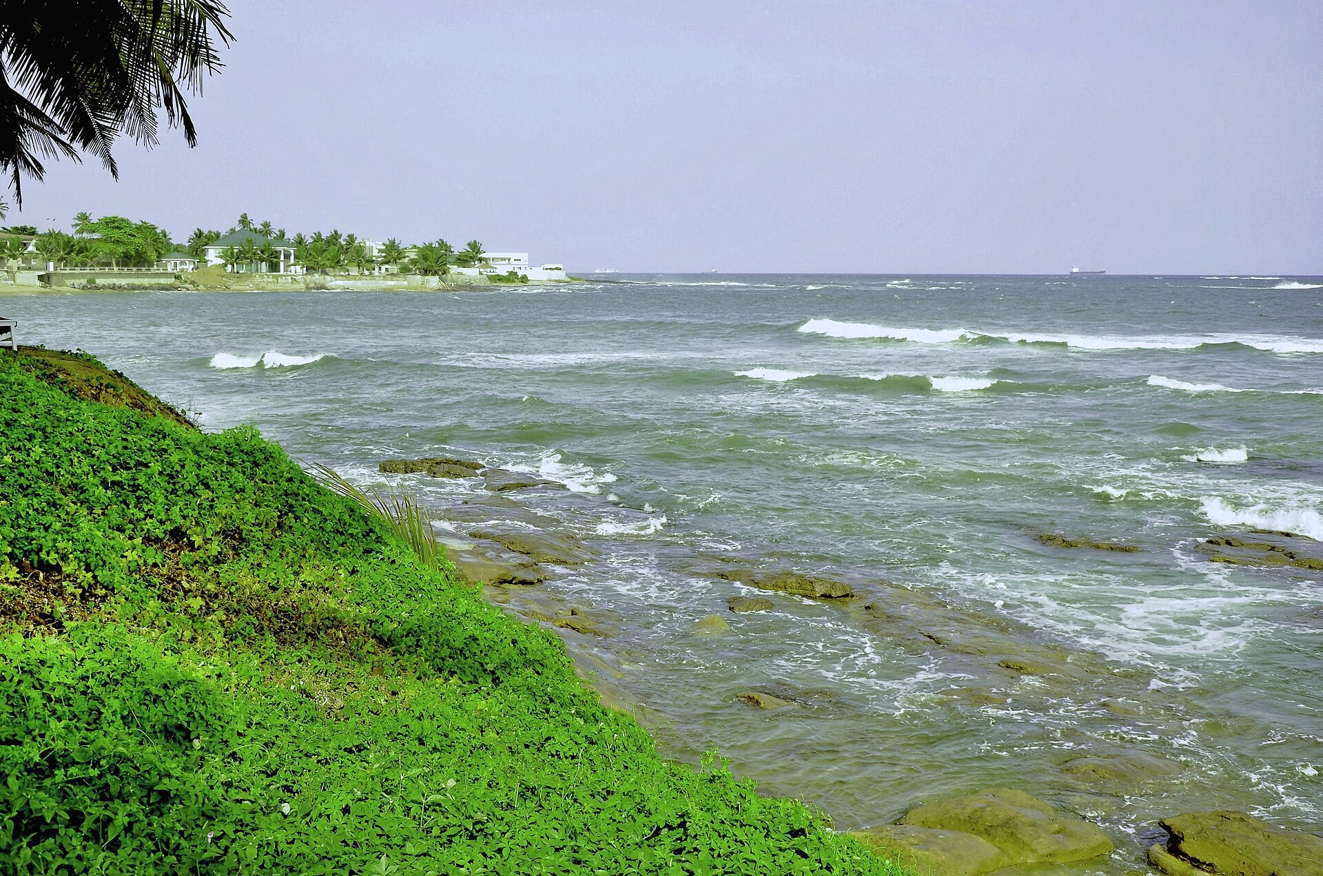 Waves on the rocky shore at Sekondi-Takoradi in Ghana, with ships on the horizon