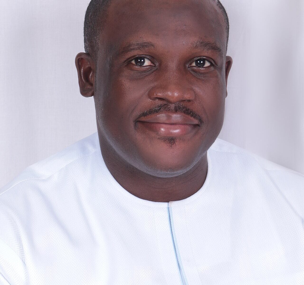 Portrait of Samuel Nartey George in a white collarless shirt against a pale background