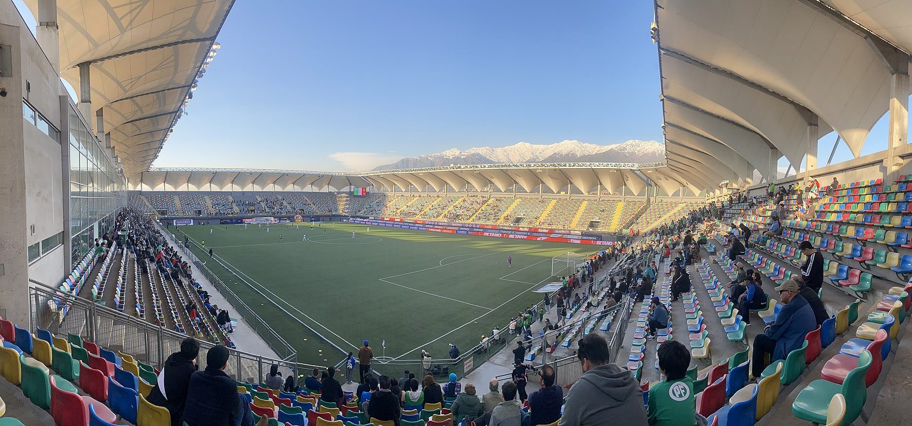 Panoramic view of the Estadio Bicentenario de La Florida in Santiago, Chile, with the snow-capped Andes behind the stands