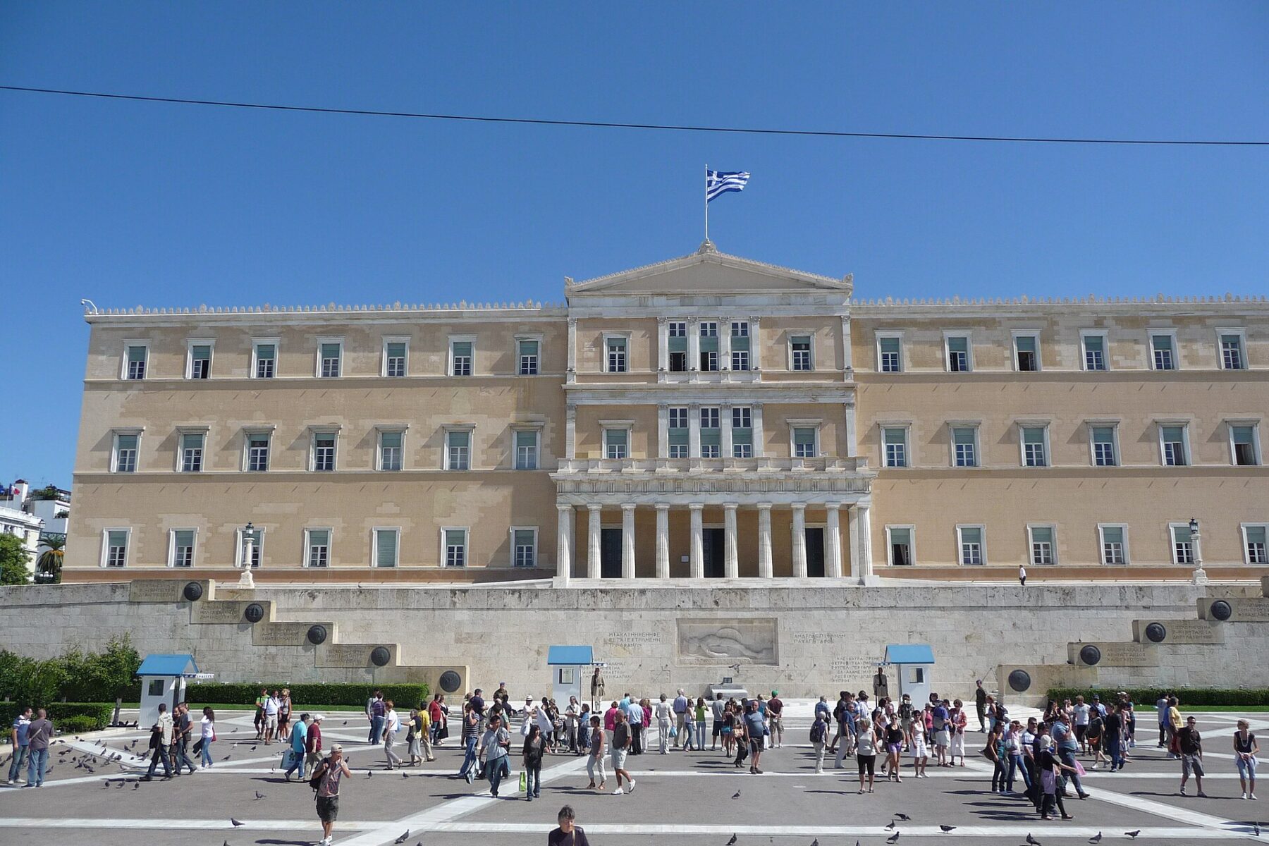 The Hellenic Parliament building on Syntagma Square in Athens with a Greek flag on the roof