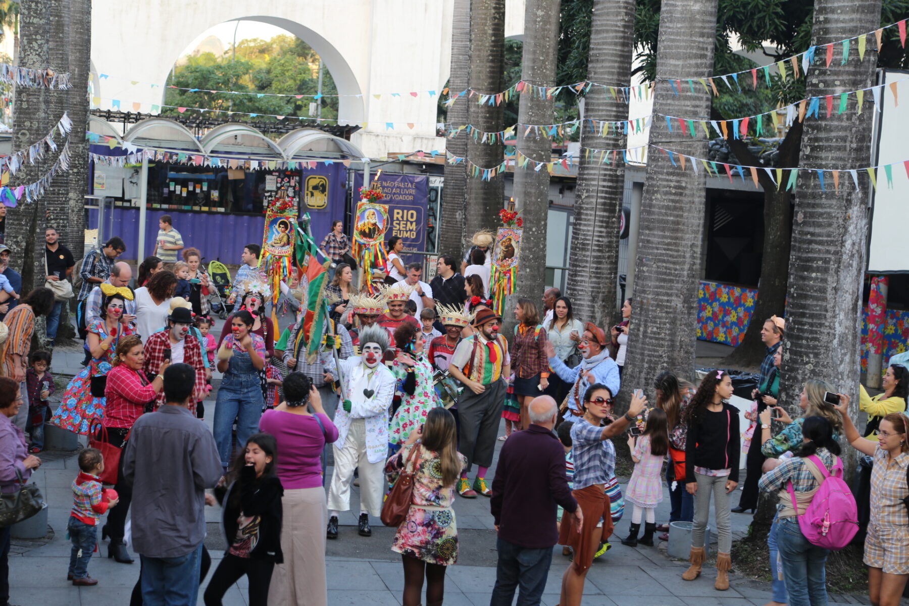 A street party crowd with bunting beside the white arches of the Arcos da Lapa in Lapa, Rio de Janeiro.