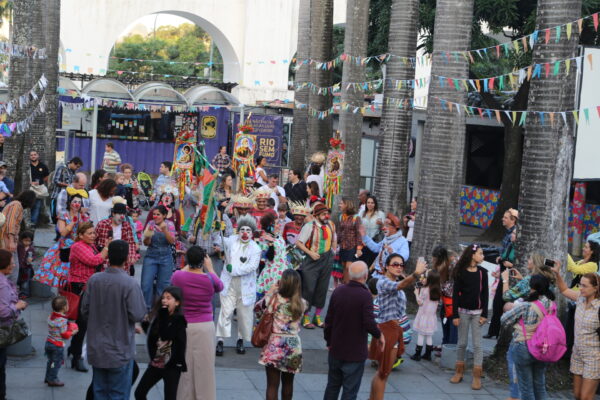 A street party crowd with bunting beside the white arches of the Arcos da Lapa in Lapa, Rio de Janeiro.