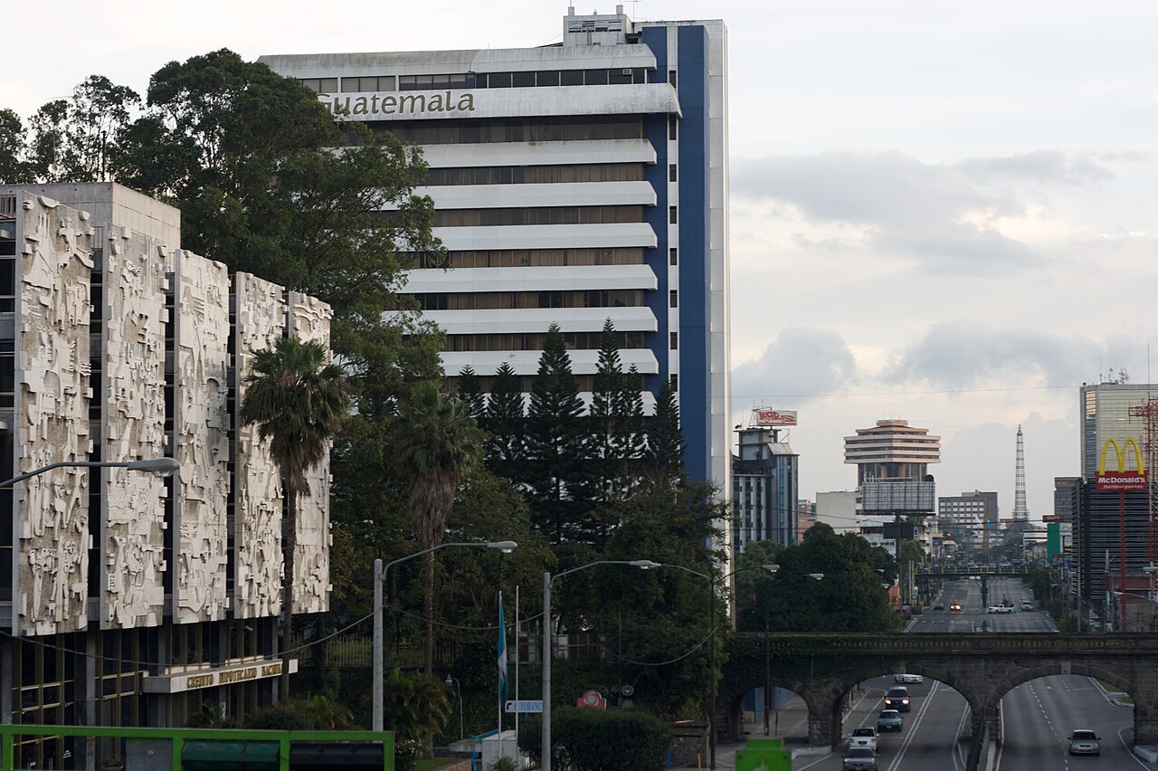 The blue and white tower of Guatemala's tourism agency beside the state mortgage bank building on a wide avenue in central Guatemala City