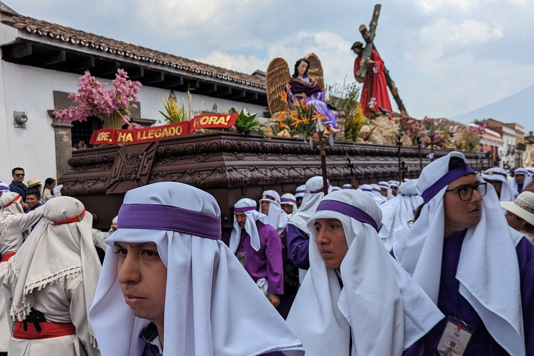 Bearers in purple and white robes carry a Holy Week float of Jesus carrying the cross through a street in Antigua Guatemala