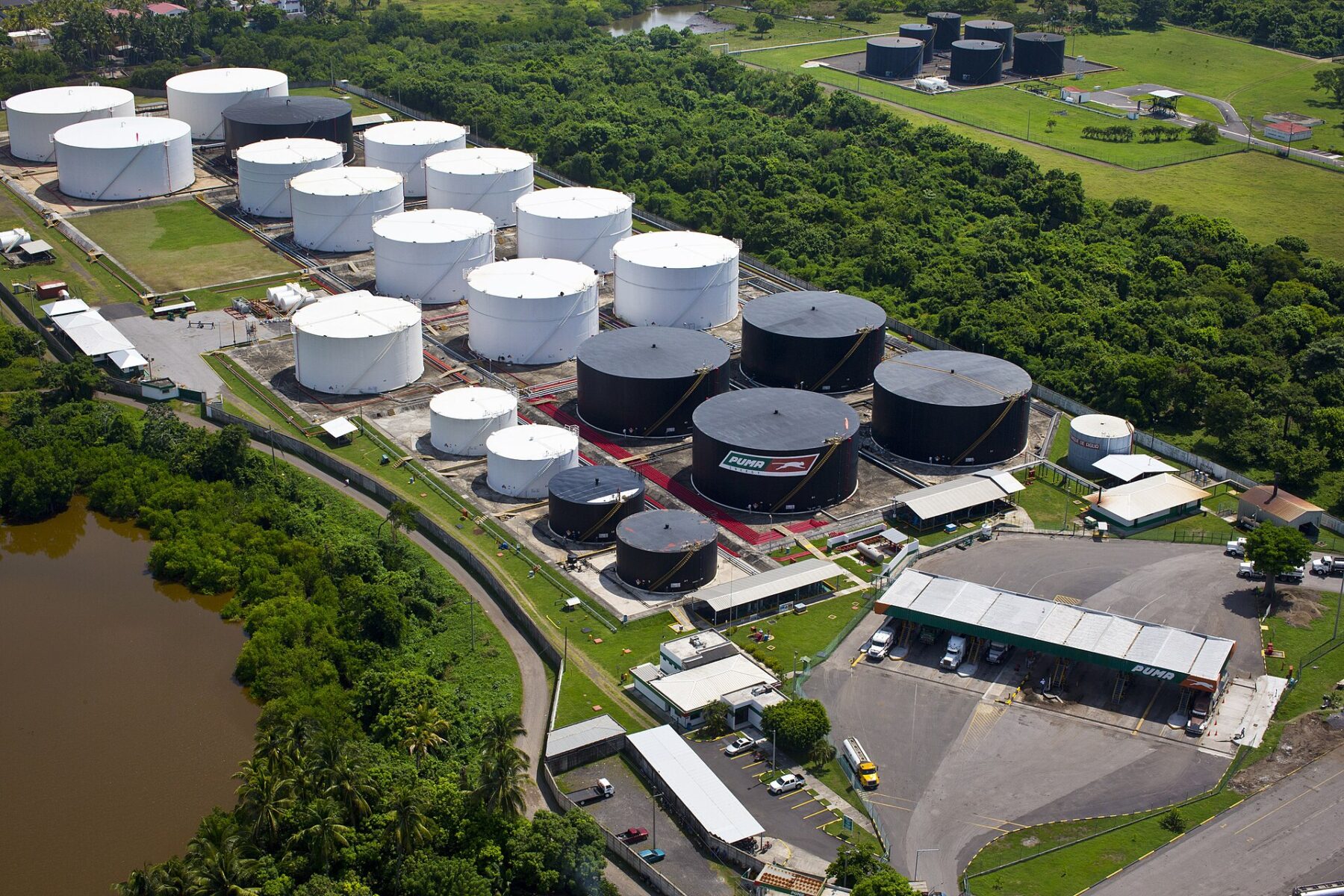 Aerial view of white and black fuel storage tanks and a tanker-truck loading bay at a Puma Energy terminal in Guatemala
