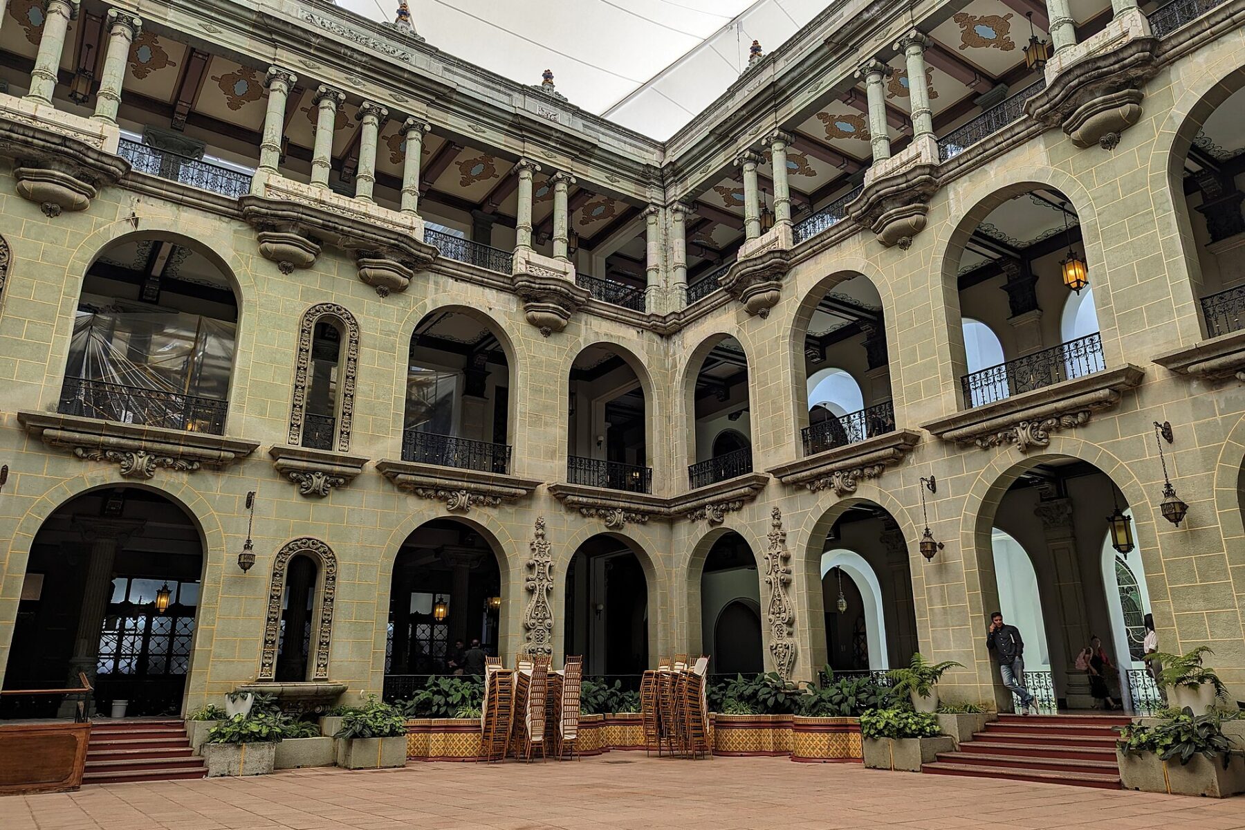 The arched courtyard of the National Palace of Culture in Guatemala City, with stacked chairs and balconies on three levels