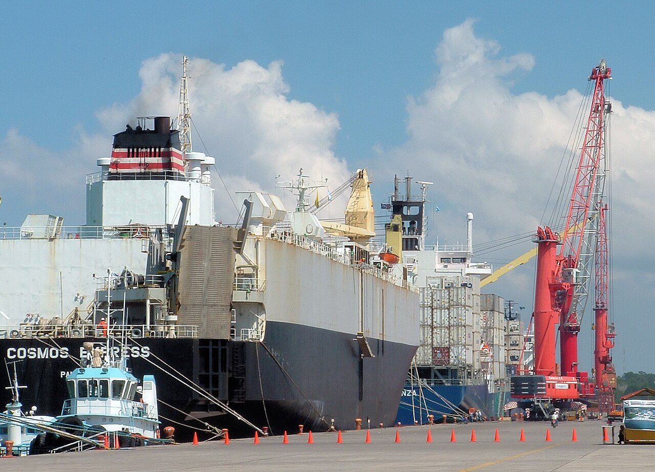 Vehicle carrier Cosmos Express and a container ship moored beside red cranes at Puerto Quetzal, Guatemala