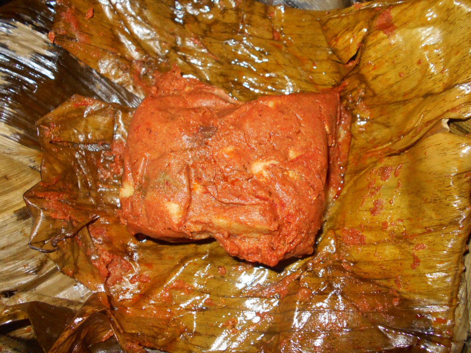 Guatemala food: an opened tamal colorado on its leaf wrapping