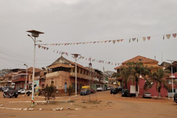 A street corner in Bissau Velho, the old centre of Bissau, with colonial-era buildings, parked cars and strings of coloured bunting across the road