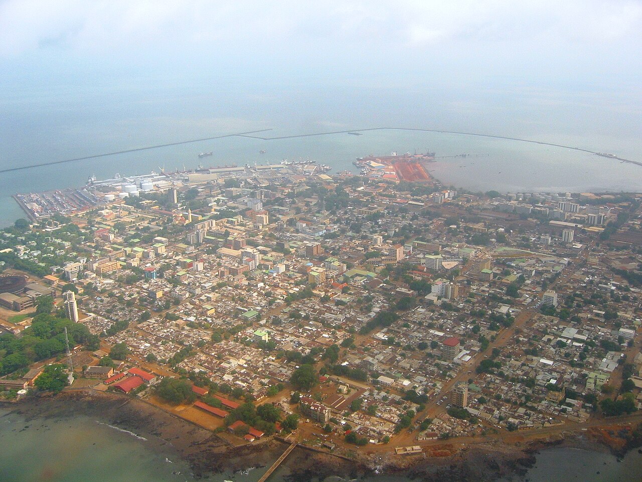 Aerial view of the Conakry peninsula with the port, a long breakwater and dense city blocks
