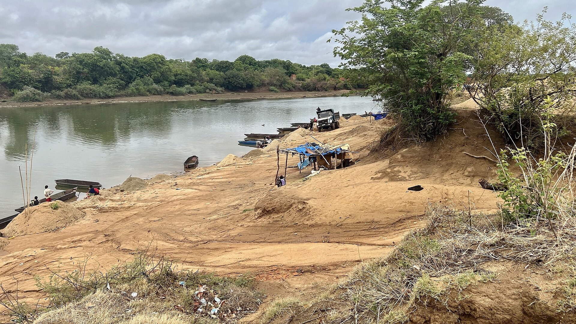 Boats, a dump truck and piles of sand on the bank of the river port at Kankan in eastern Guinea.