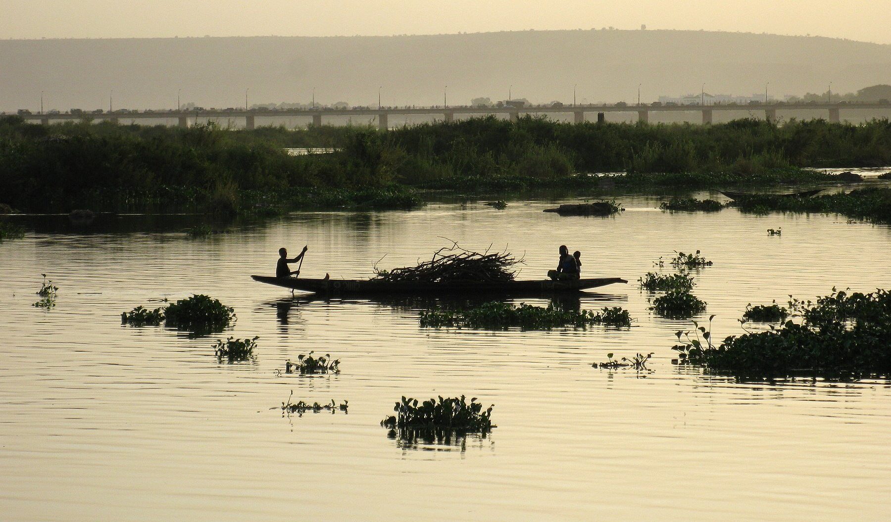 A pirogue on the Niger River in Bamako, Mali, with the King Fahd Bridge in the background