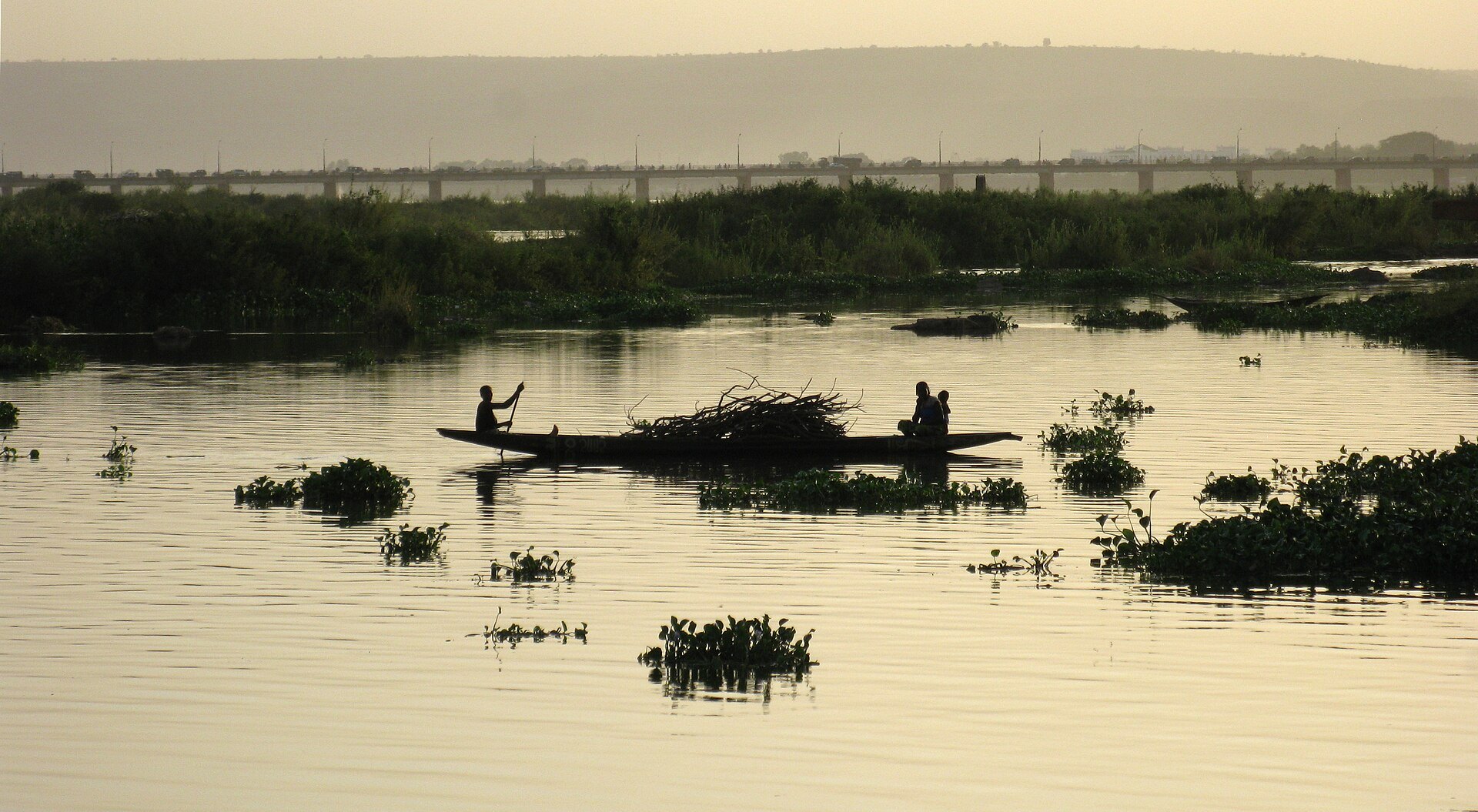 A pirogue on the Niger River in Bamako, Mali, with the King Fahd Bridge in the background