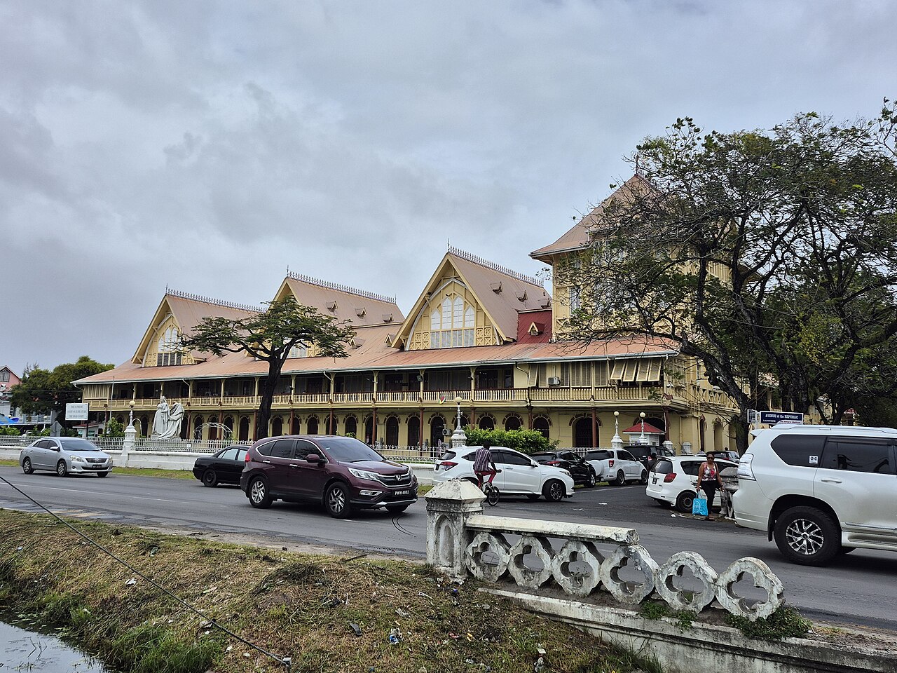 Yellow colonial-era High Court building with red roofs and gables behind a busy road in Georgetown, Guyana