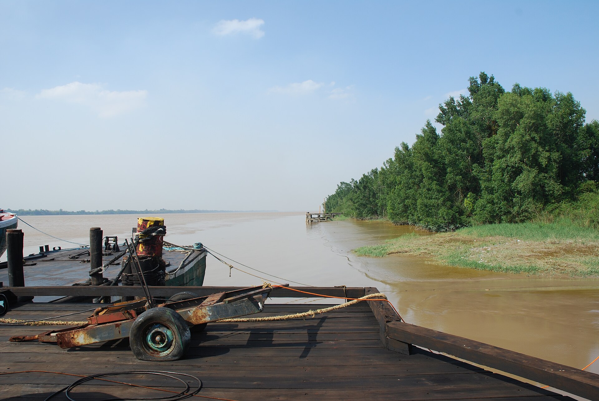 A wooden jetty on the Demerara River in Guyana with mangroves on the bank