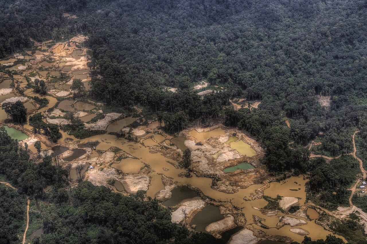 Aerial view of gold mining pits and muddy ponds cut into dense rainforest near Mahdia, Guyana