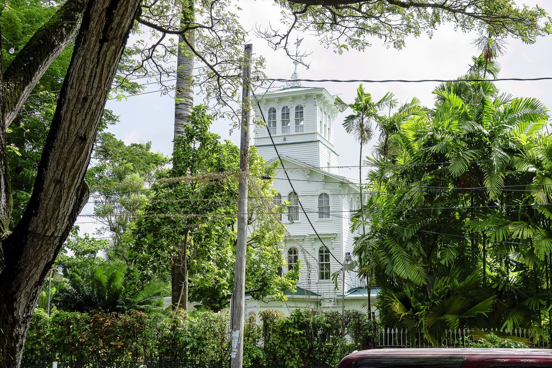 The white wooden tower of State House in Georgetown, Guyana, seen through trees