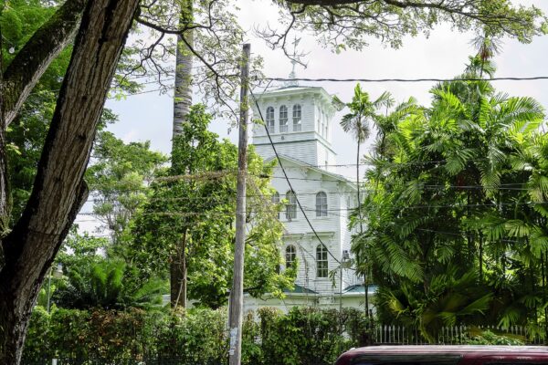 The white wooden tower of State House in Georgetown, Guyana, seen through trees