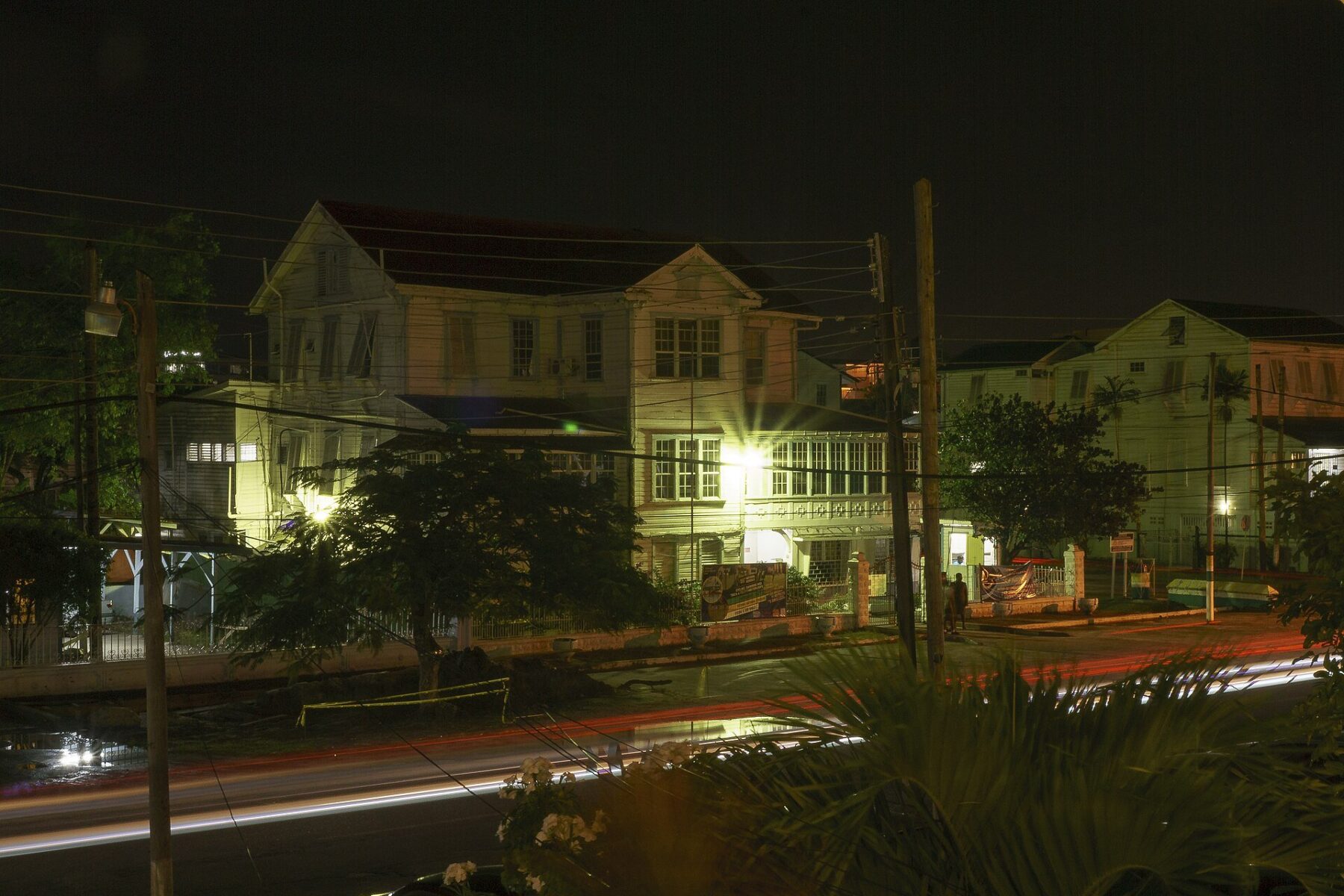Wooden colonial-era houses on a Georgetown street at night with light trails from passing traffic