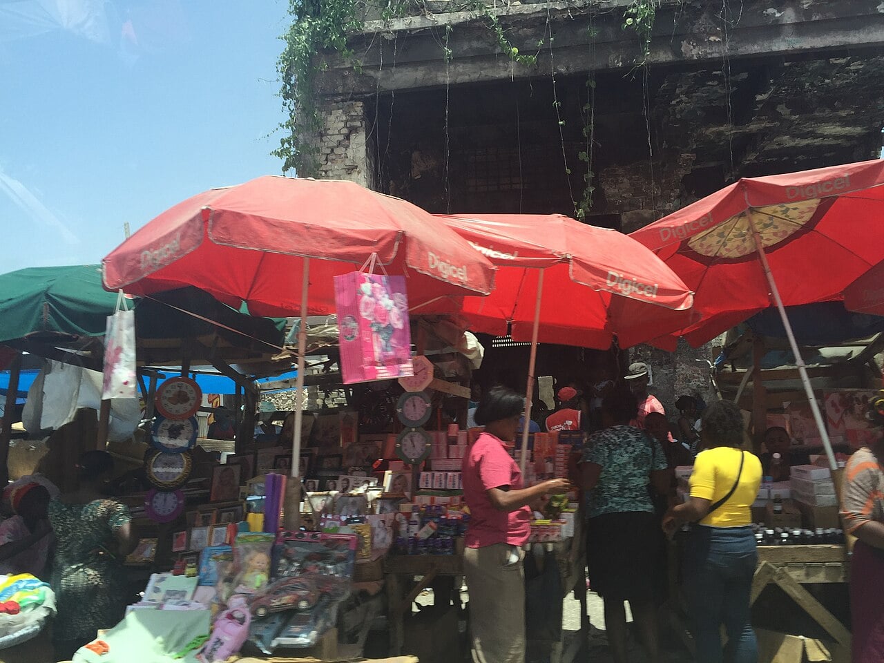Street vendors in Port-au-Prince selling goods under red umbrellas bearing the Digicel logo