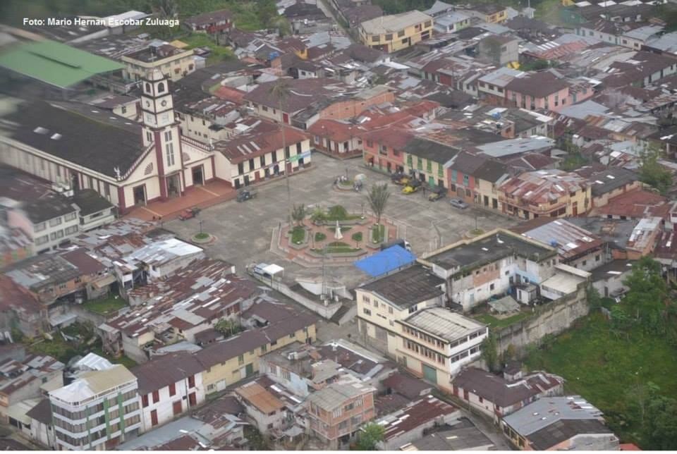 Aerial view of Herveo with a white church on its main square, surrounded by red and grey roofs on a green hillside