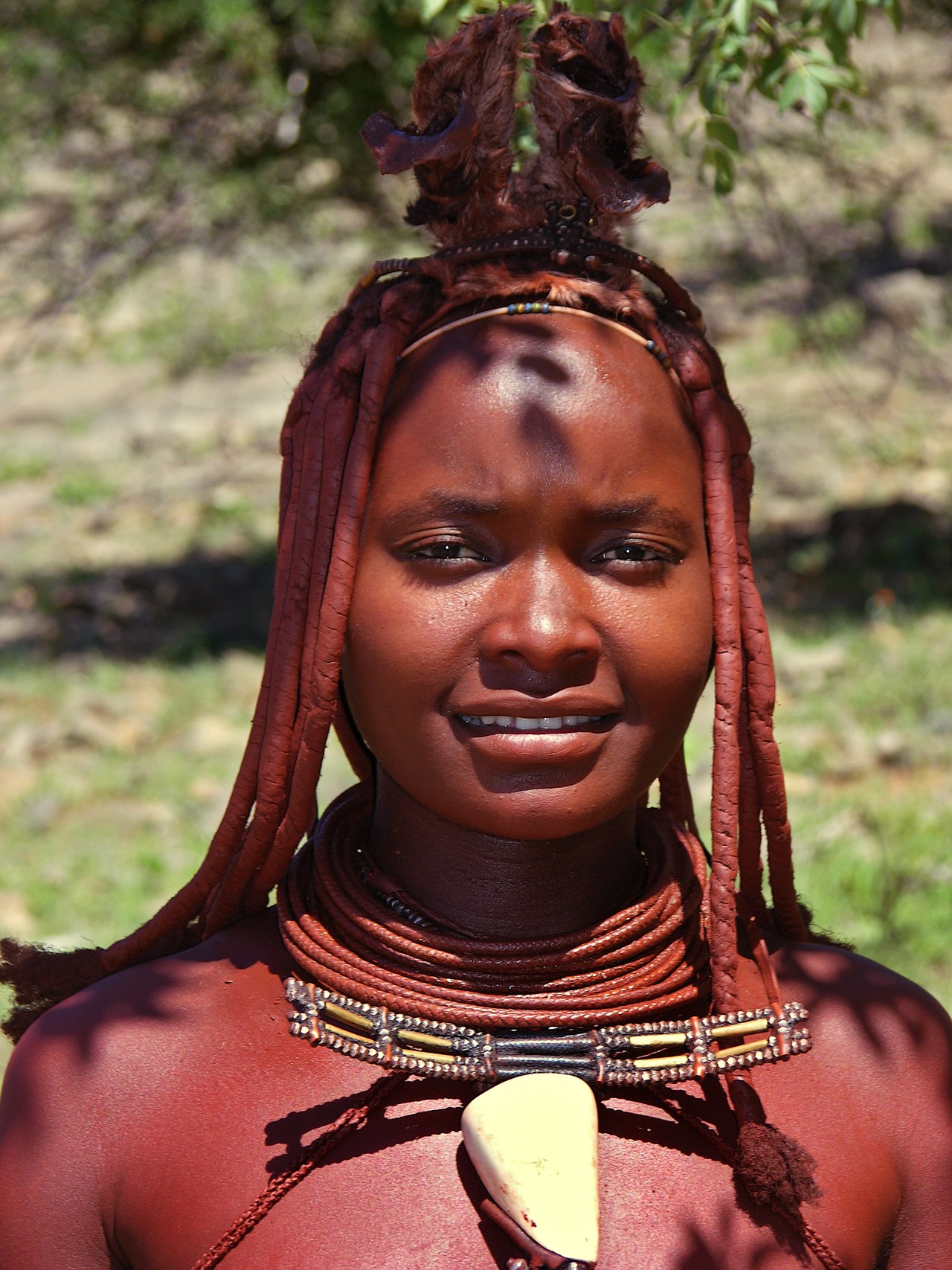 Portrait of a Himba woman from northern Namibia with braided, ochre-coloured hair and a shell pendant