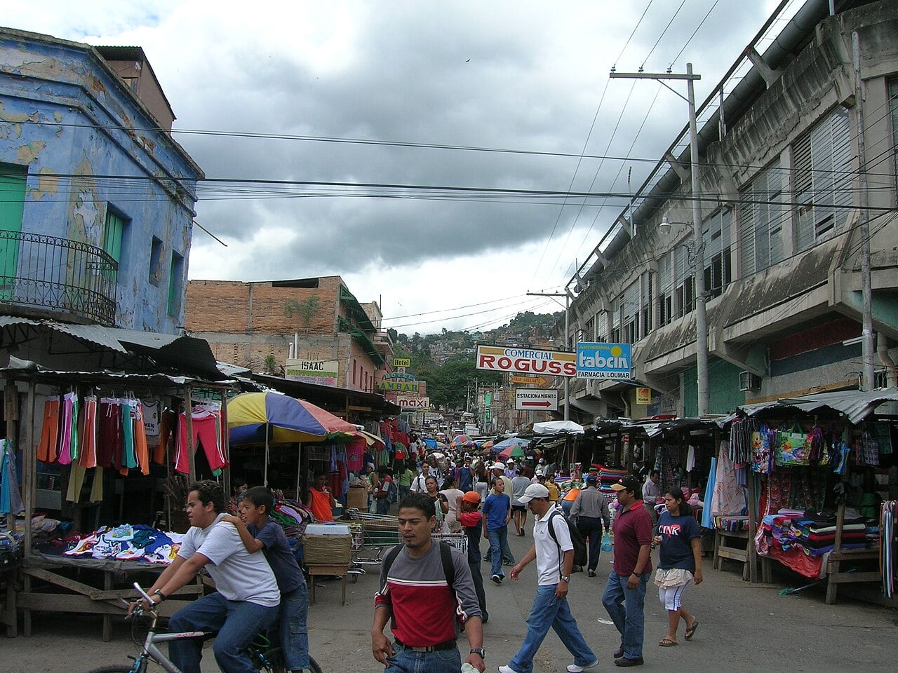 Crowded street market in Tegucigalpa, Honduras, with vendors, shoppers and hills in the background